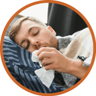 Sick bearded man who has bad cold or seasonal flu sitting on couch at home. Guy with fever wearing warm plaid shivering with worried face expression